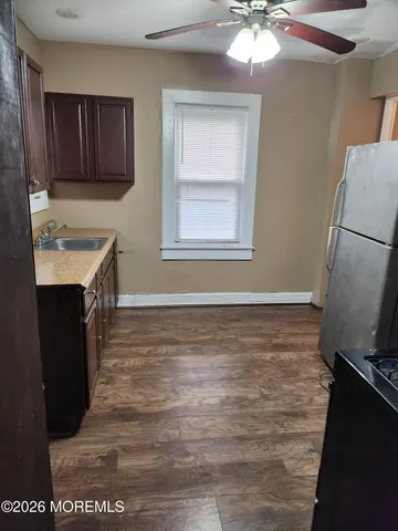 a room with granite countertop a sink a stove a refrigerator and cabinets