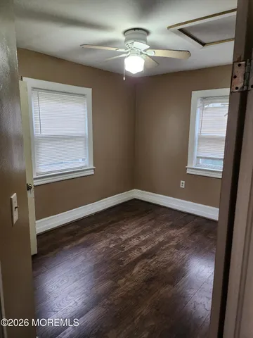 an empty room with wooden floor chandelier fan and windows