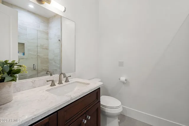 a bathroom with a granite countertop sink a toilet and a mirror