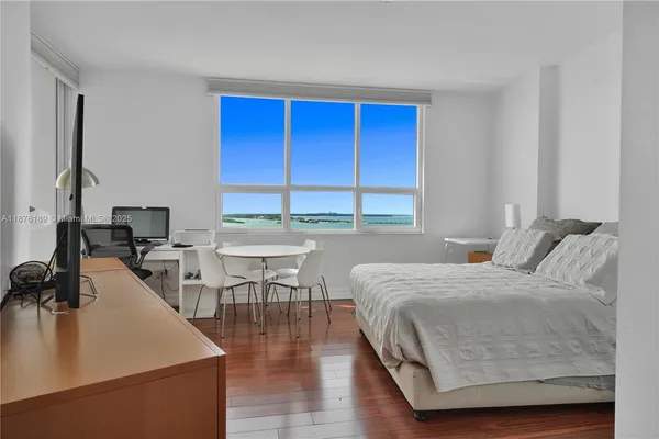 a bedroom with a bed a table and a dresser next to a window