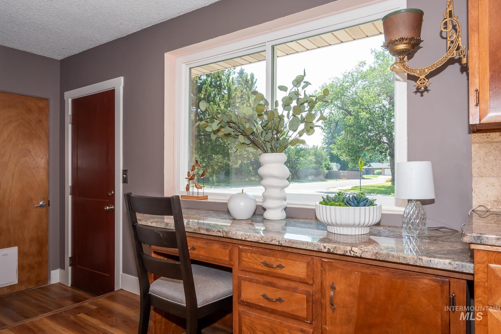 3706 West Clement Road Boise, ID 83704 - Photo 17 of 36 Elegant kitchen workspace featuring warm wood cabinetry with multiple storage drawers and cabinet doors, granite countertops, and a substantial window with white trim framing mature landscaping