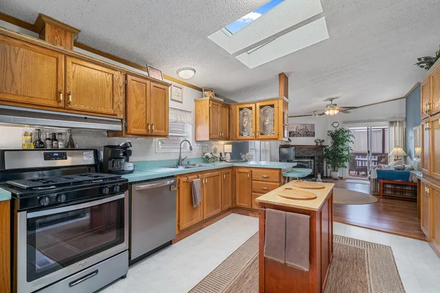 a kitchen with stainless steel appliances granite countertop a stove top oven a sink dishwasher and cabinets with wooden floor