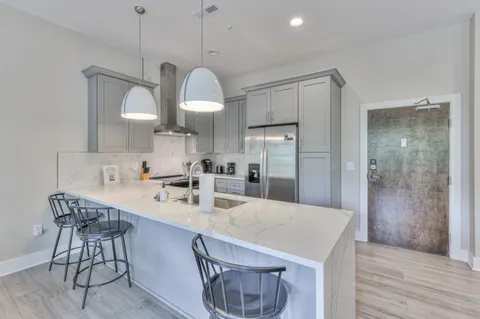 a kitchen with kitchen island granite countertop a sink a counter space appliances and cabinets