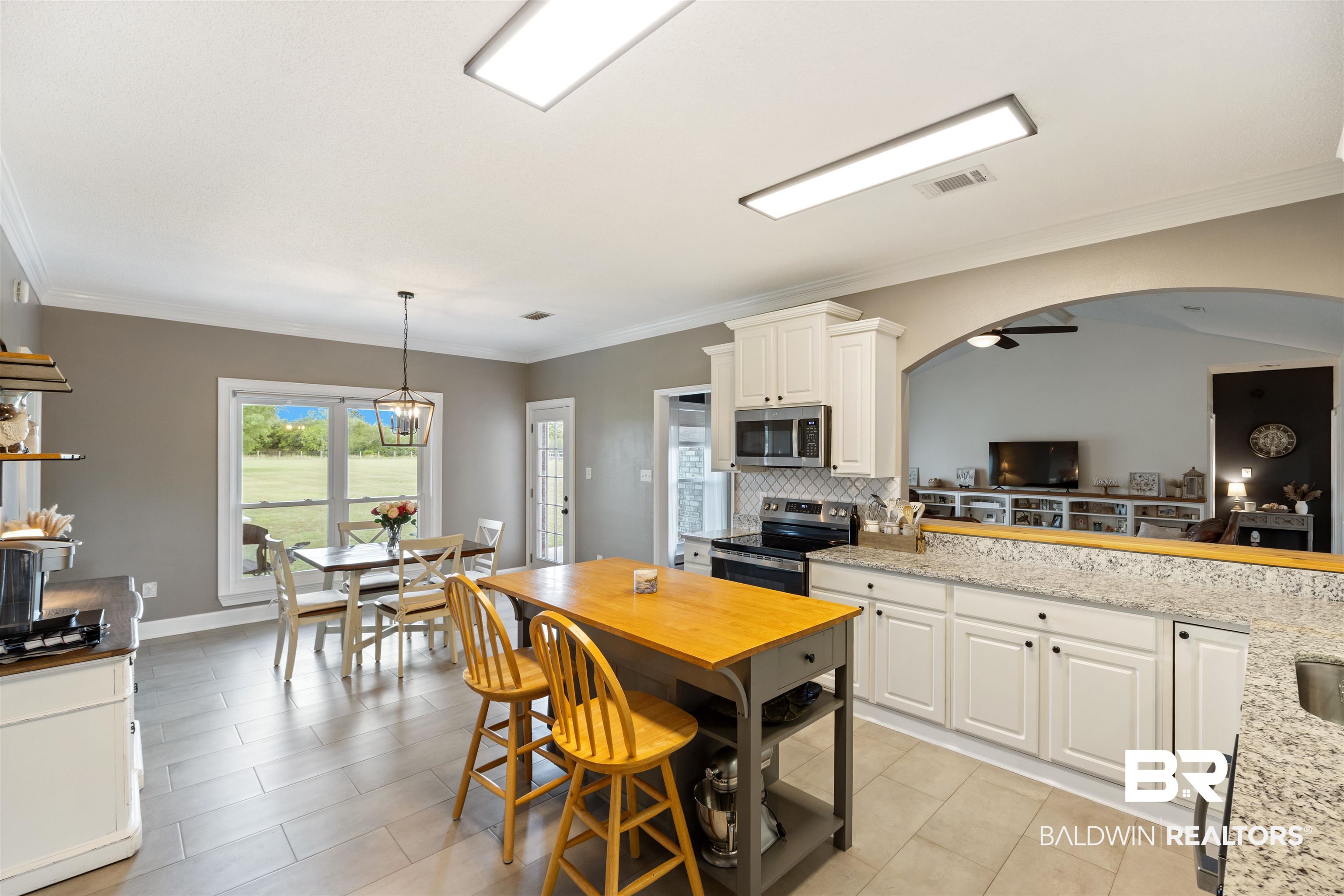 9855 Stucki Road Elberta, AL 36530 - Photo 23 of 54 Kitchen with ornamental molding, stainless steel appliances, backsplash, light stone counters, and white cabinetry
