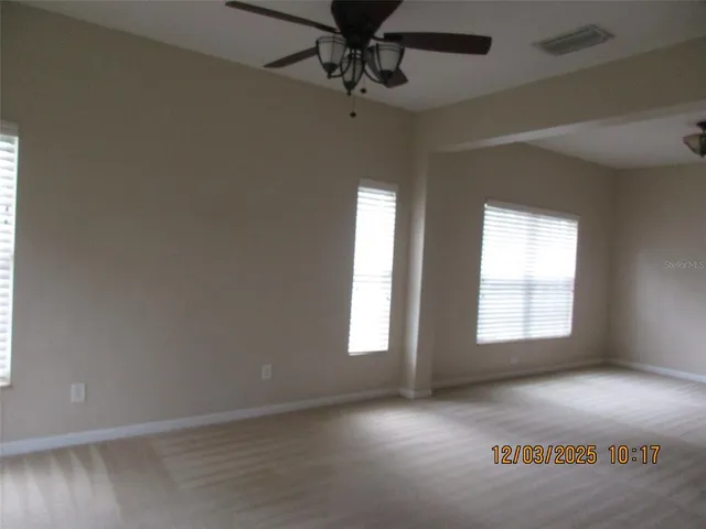 an empty room with windows and fan
