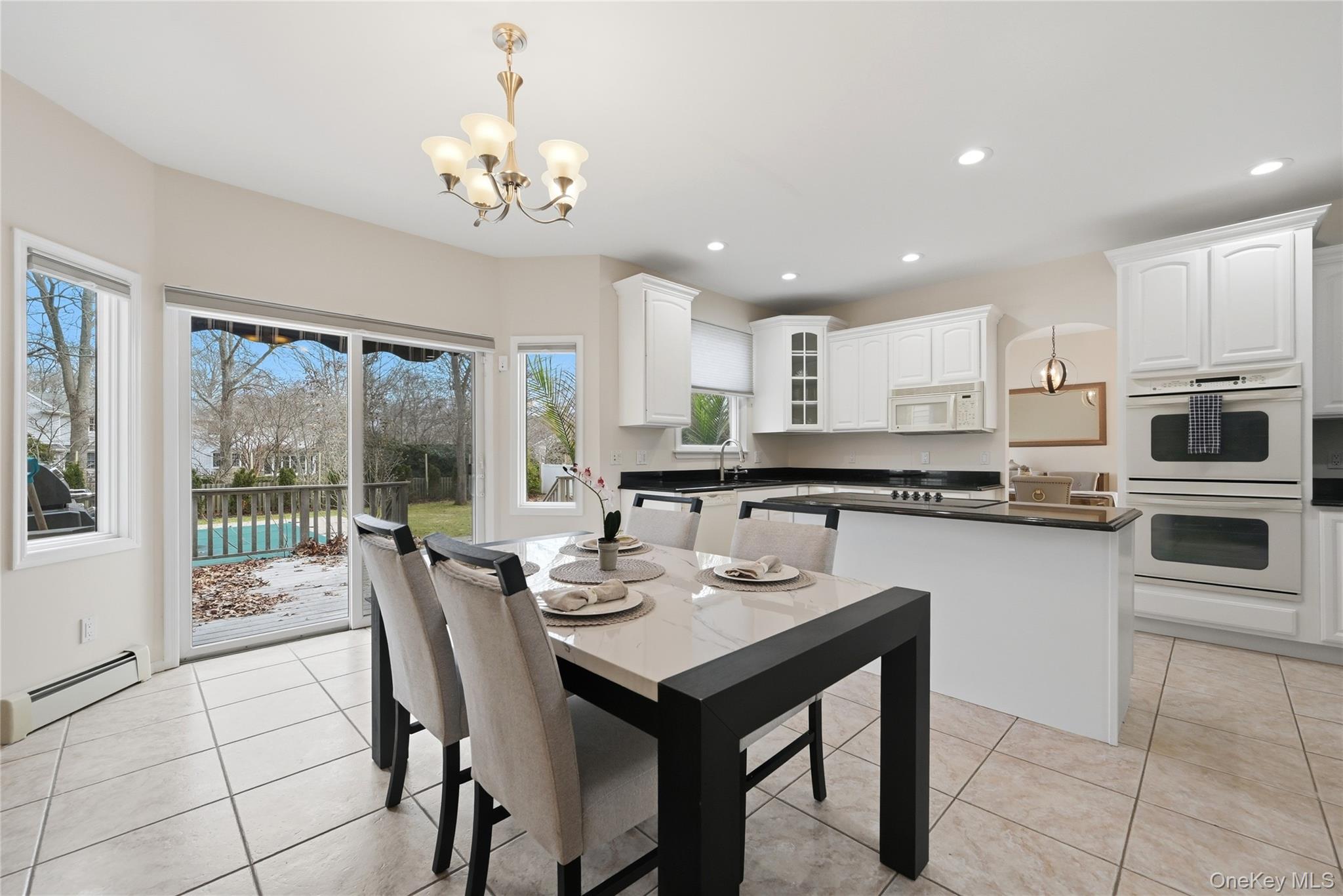 5 Mill Race Road Hampton Bays, NY 11946 - Photo 17 of 34 a kitchen with a dining table chairs and refrigerator
