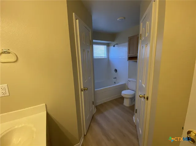 an empty room with a chandelier fan and windows