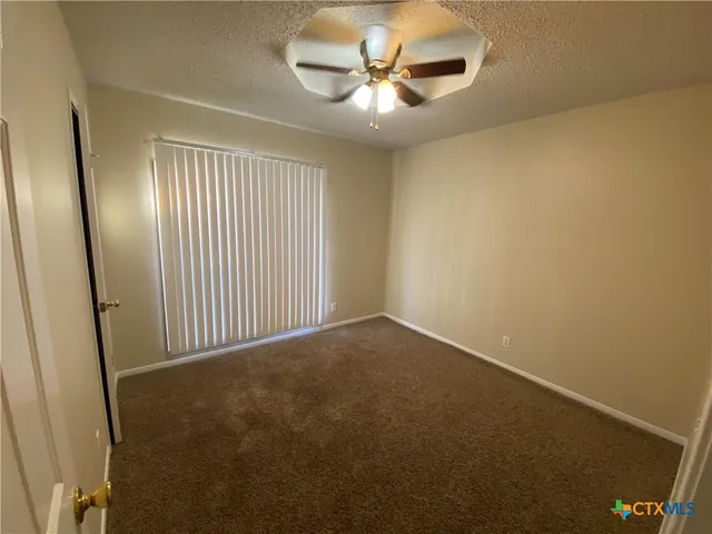 an empty room with a ceiling fan and a window