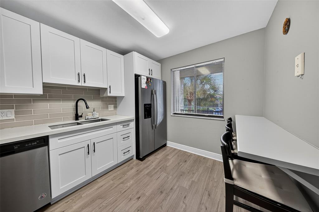 412 Lakeview Drive, Unit 202 Weston, FL 33326 - Photo 9 of 34 a kitchen with stainless steel appliances granite countertop a refrigerator a sink dishwasher a stove and white countertops with wooden floor