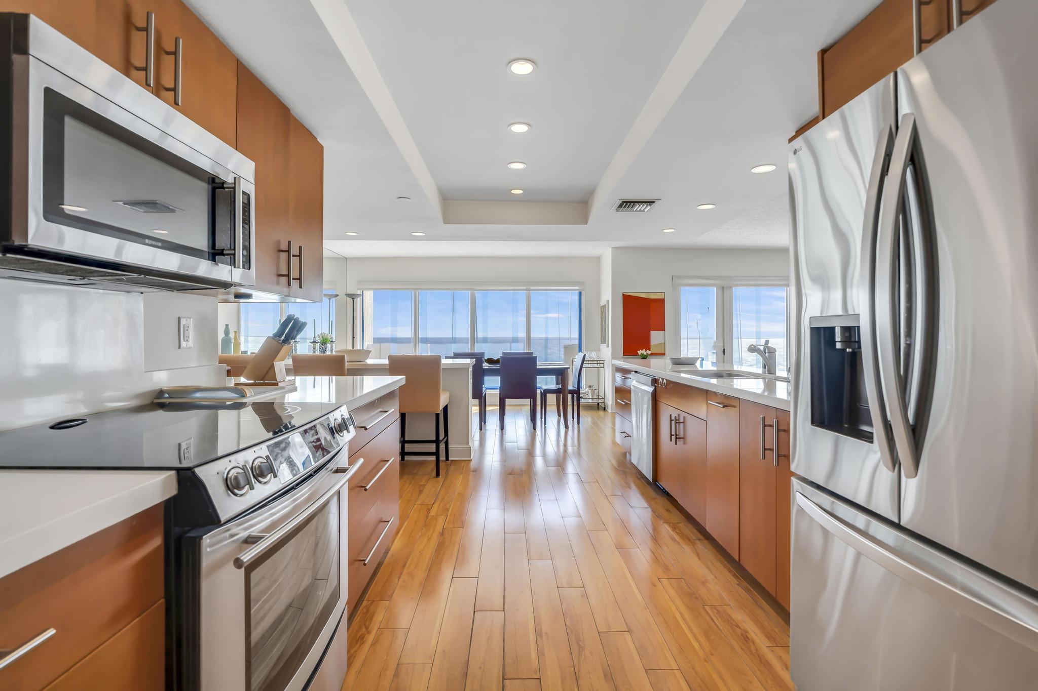 4301 North Ocean Boulevard, Unit 1002 Boca Raton, FL 33431 - Photo 11 of 71 a kitchen with stainless steel appliances granite countertop a refrigerator a stove top oven a sink dishwasher and a refrigerator with wooden floor