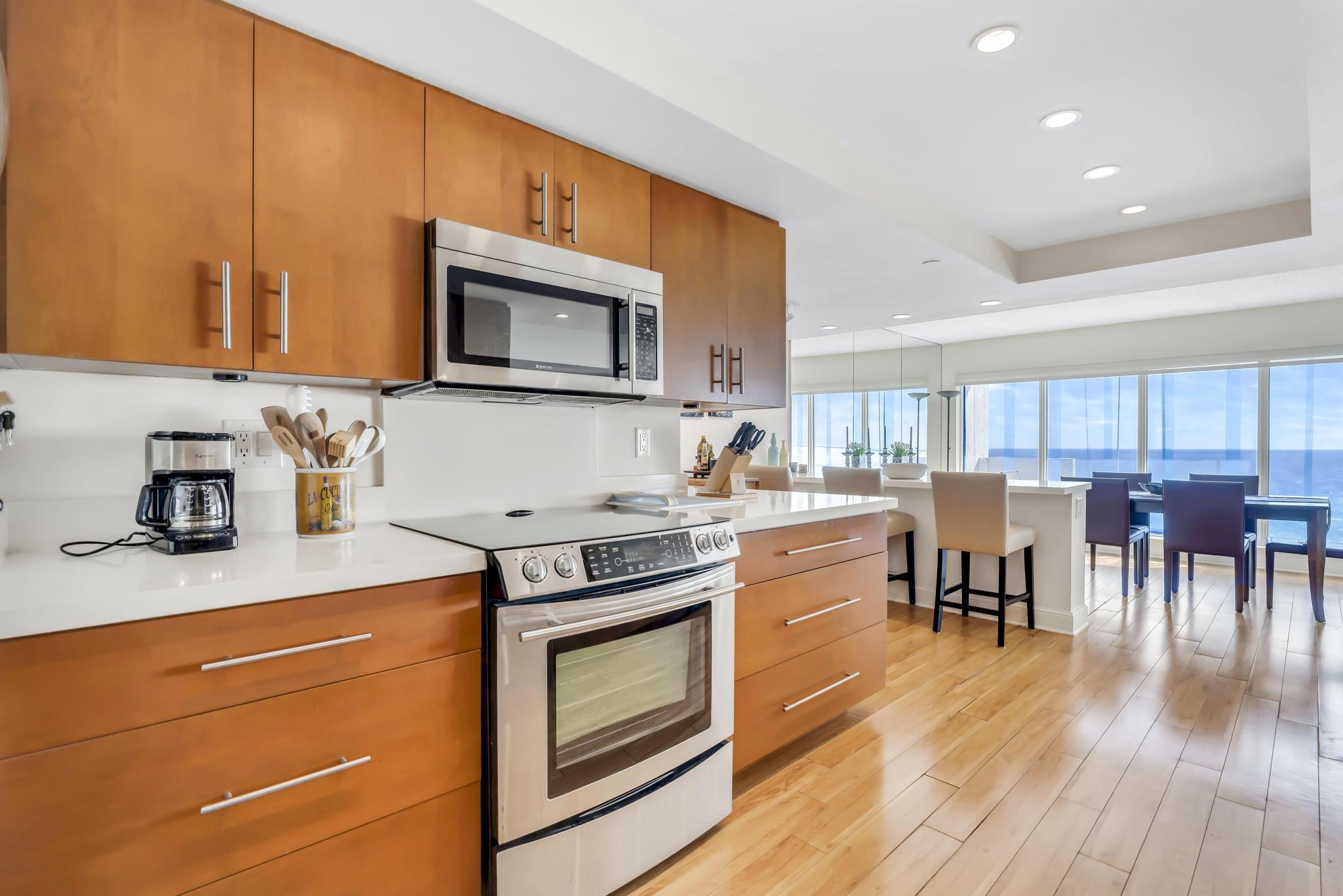 4301 North Ocean Boulevard, Unit 1002 Boca Raton, FL 33431 - Photo 13 of 71 a kitchen with stainless steel appliances a stove a sink cabinets and a dining table