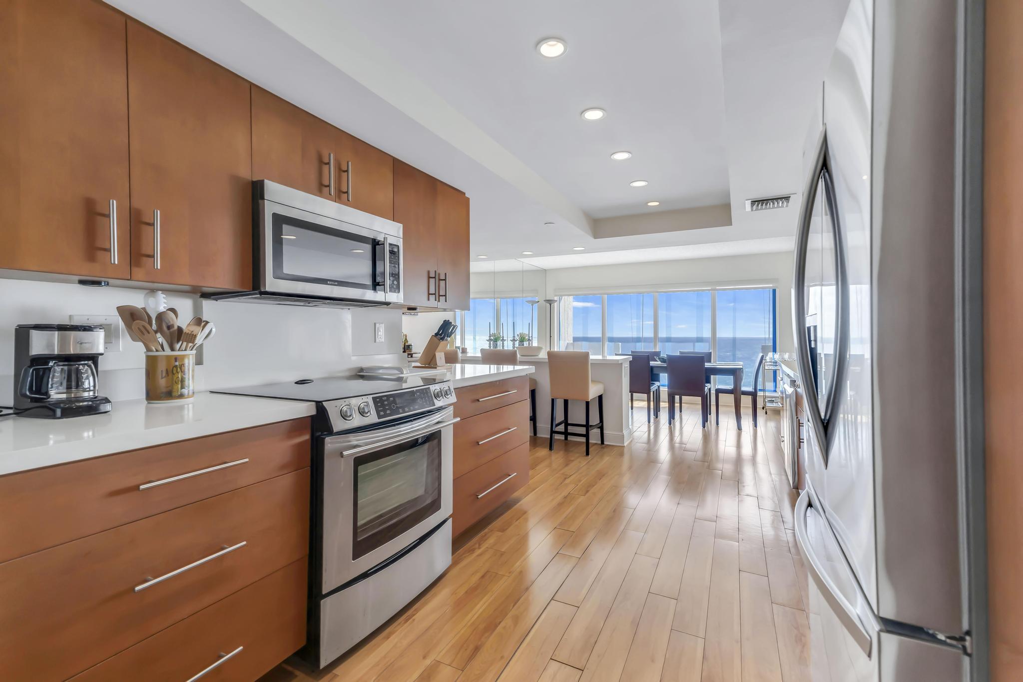 4301 North Ocean Boulevard, Unit 1002 Boca Raton, FL 33431 - Photo 10 of 71 a kitchen with stainless steel appliances granite countertop a stove top oven a sink a dining table and chairs with wooden floor