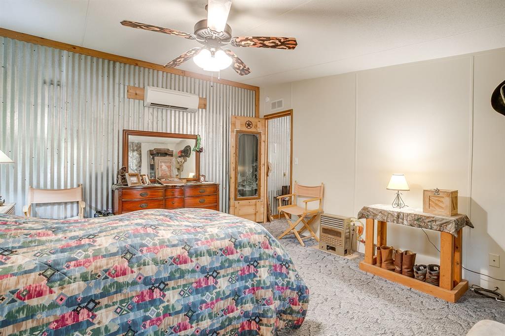 436 Luke Road Springtown, TX 76082 - Photo 22 of 39 Carpeted bedroom featuring ceiling fan, a decorative wall, and a wall mounted AC