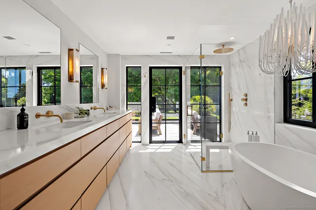 a large white kitchen with kitchen island a large window a sink and stainless steel appliances