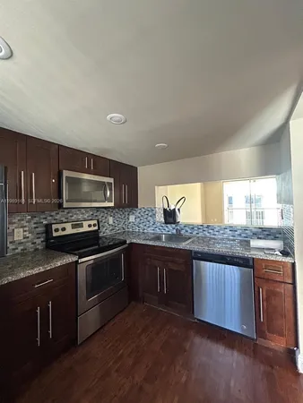 a kitchen with stainless steel appliances granite countertop a stove a sink and a microwave