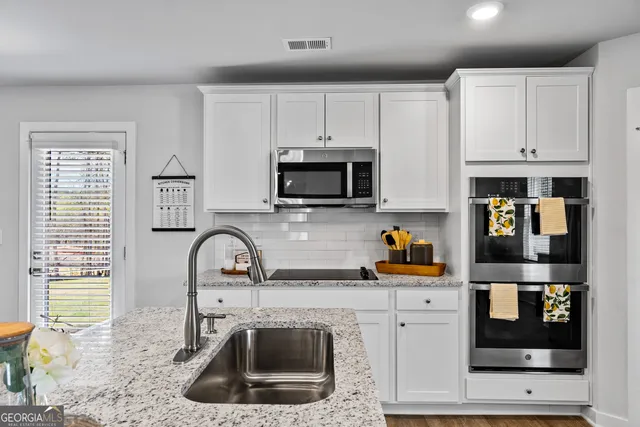 a kitchen with stainless steel appliances granite countertop a table chairs microwave and refrigerator