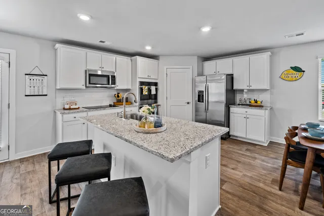 a kitchen with stainless steel appliances granite countertop a table chairs sink and cabinets