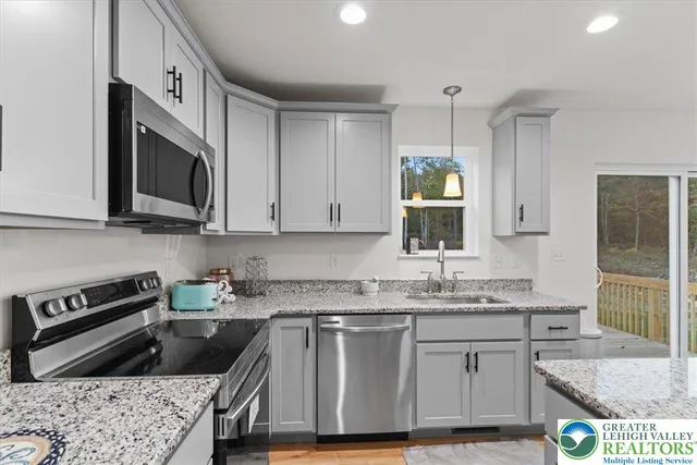 a kitchen with granite countertop a sink a stove and cabinets