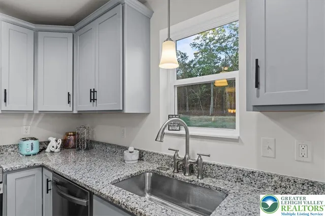 a kitchen with granite countertop a sink window and cabinets