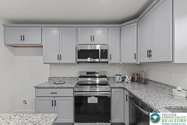 a kitchen with granite countertop white cabinets and stainless steel appliances