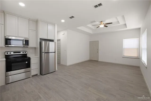 a view of a kitchen with a sink a ceiling fan and stainless steel appliances