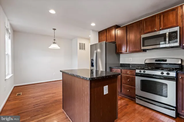 a kitchen with stainless steel appliances granite countertop a stove a refrigerator and a microwave