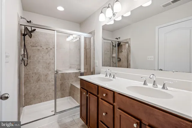 a bathroom with a double vanity sink mirror and shower