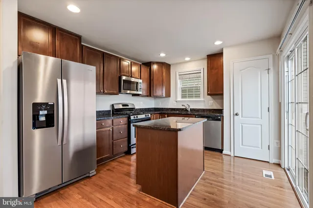 a kitchen with stainless steel appliances granite countertop a refrigerator and a stove top oven