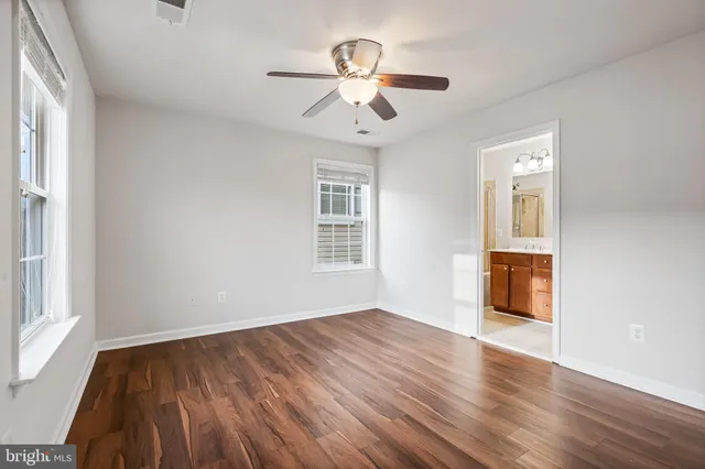 a view of empty room with wooden floor and fan