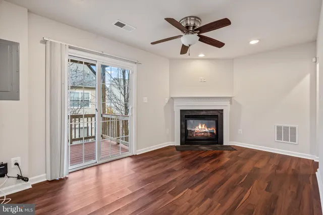a view of an empty room with wooden floor fireplace and a window