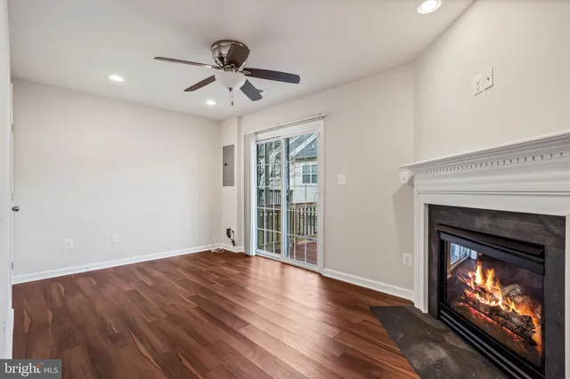a view of an empty room with wooden floor fireplace and a window