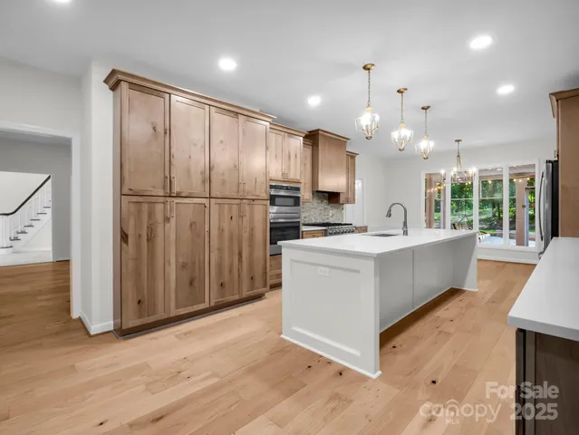 a large white kitchen with kitchen island granite countertop a large counter top and stainless steel appliances