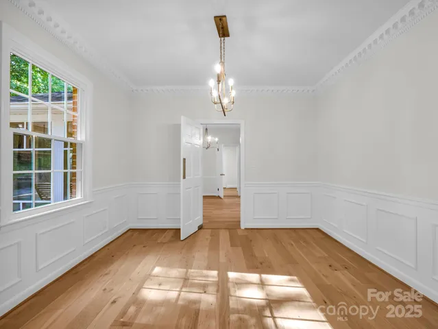 a view of an empty room with wooden floor fireplace and a window