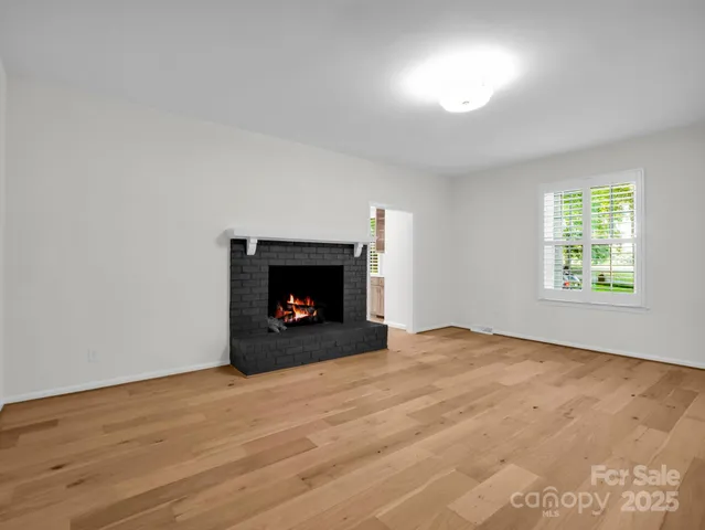 an empty room with wooden floor fireplace and windows
