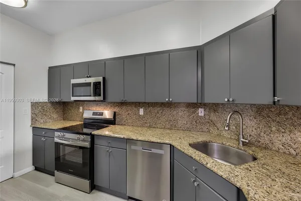 a kitchen with granite countertop a sink stove and microwave
