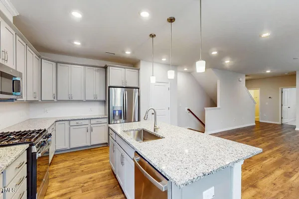 a kitchen with stainless steel appliances granite countertop a sink a stove a refrigerator and a oven