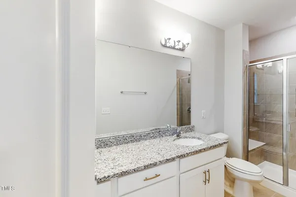 a bathroom with a granite countertop sink a toilet and a mirror
