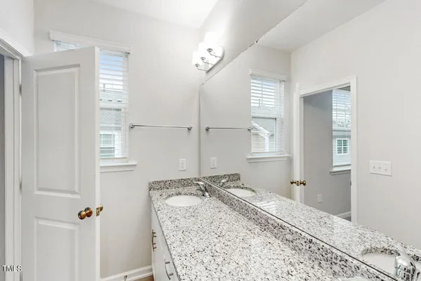 a bathroom with a granite countertop sink a toilet a mirror and window