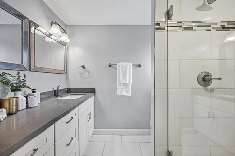 a bathroom with a granite countertop sink a mirror and shower