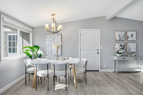a dining room with wooden floor a chandelier a wooden table and chairs
