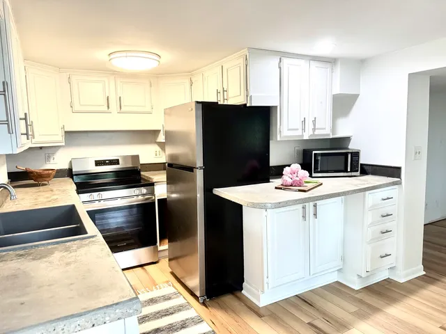 a kitchen with granite countertop white cabinets window and a sink