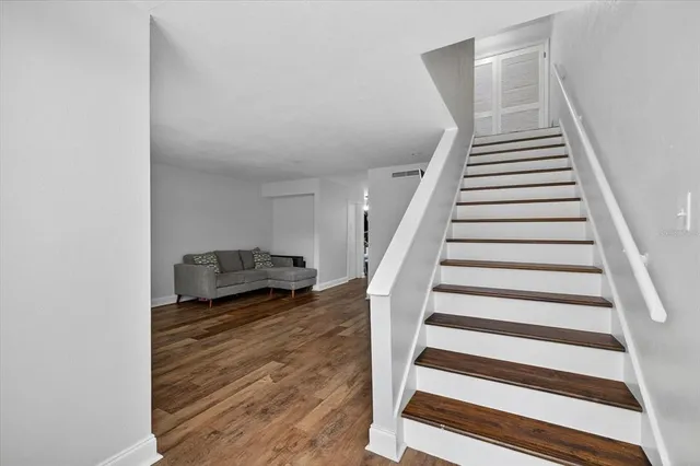 a view of a livingroom with wooden floor and stairs