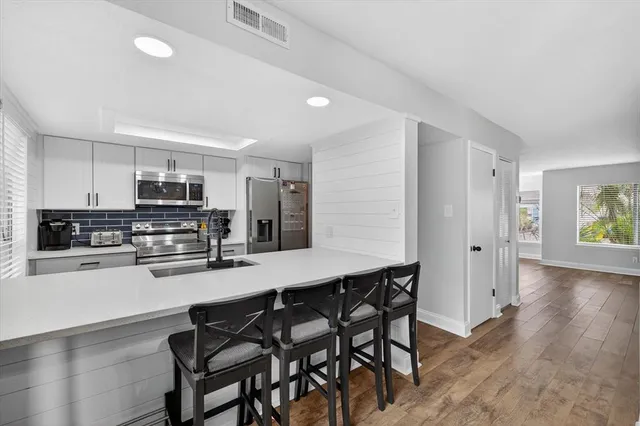 a kitchen with stainless steel appliances a microwave a stove a sink dishwasher and a refrigerator with wooden floor