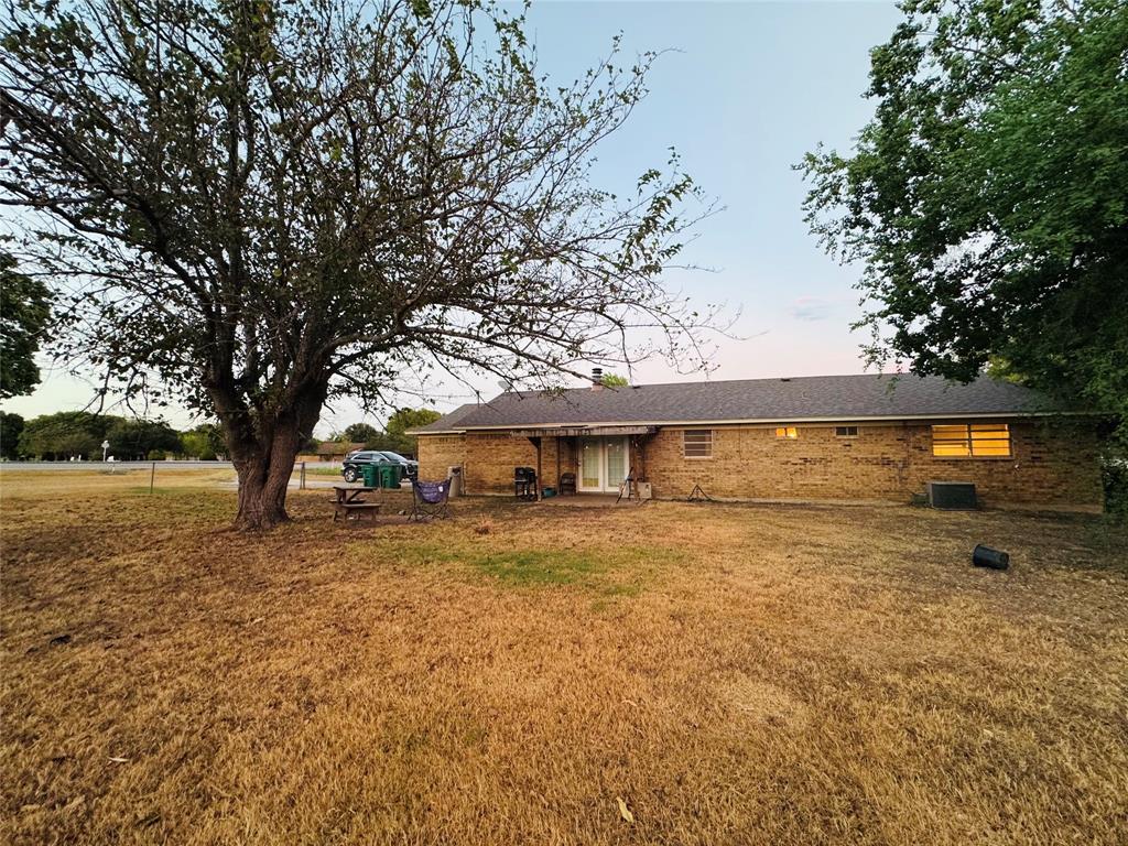721 Mackey Ranch Road Bruceville-Eddy, TX 76524 - Photo 27 of 33 Brick exterior with a dark shingle roof, mature trees, and a spacious backyard