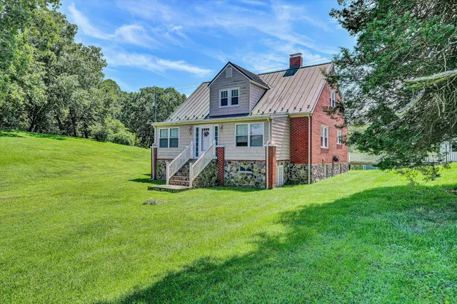 a view of a house with a big yard potted plants and large tree