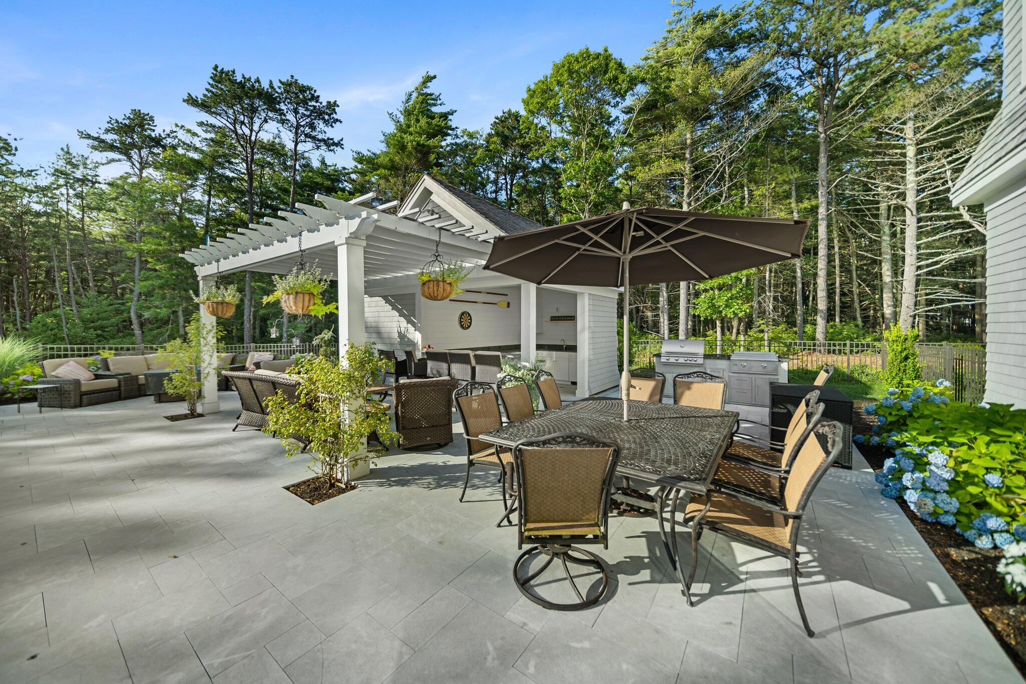 444 Vineyard Road Cotuit, MA 02635 - Photo 23 of 59 a view of a patio with a table and chairs under an umbrella