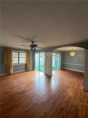 a view of an empty room with window and wooden floor