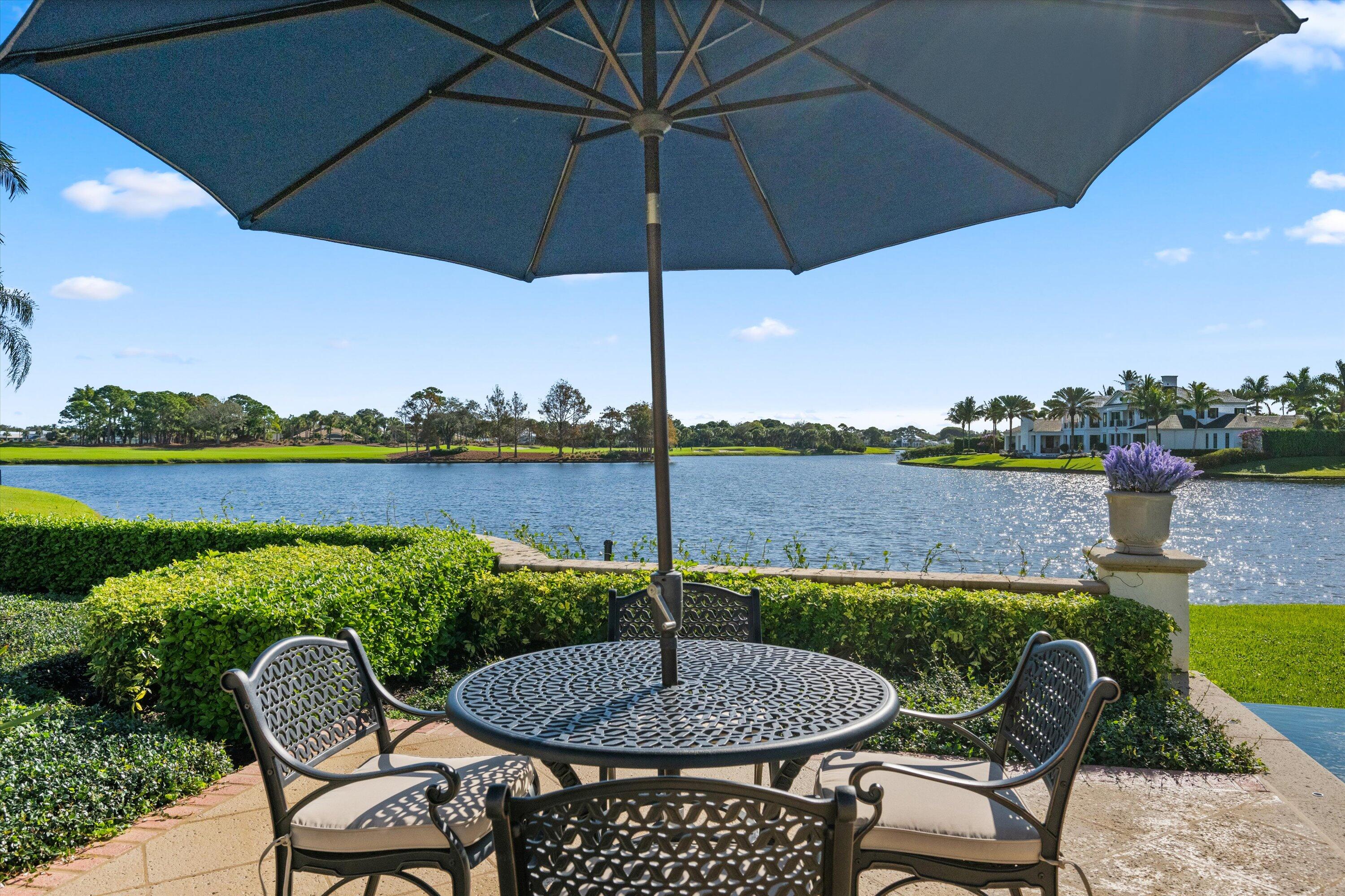 258 Locha Drive Jupiter, FL 33458 - Photo 64 of 76 a patio with a table and chairs under an umbrella