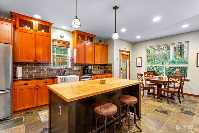 a kitchen with stainless steel appliances granite countertop wooden cabinets a stove a sink a dining table and chairs