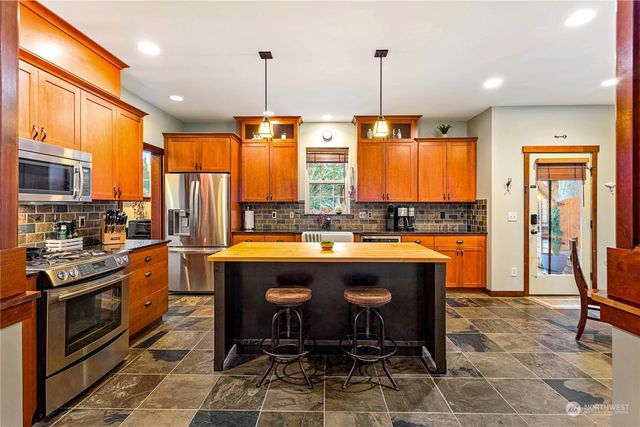 a kitchen with stainless steel appliances granite countertop a stove a sink a oven a dining table and chairs